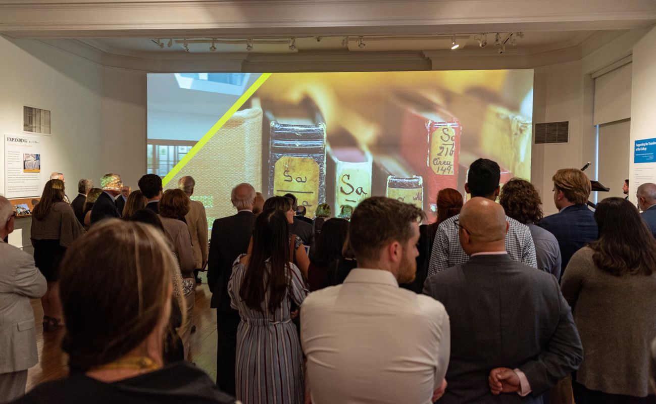 A group of people standing in front of the large screen.